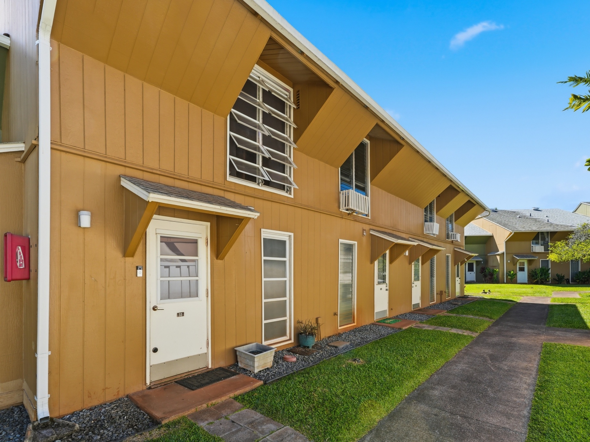 Exterior walkway view of Mililani Manor townhomes and landscaped grounds