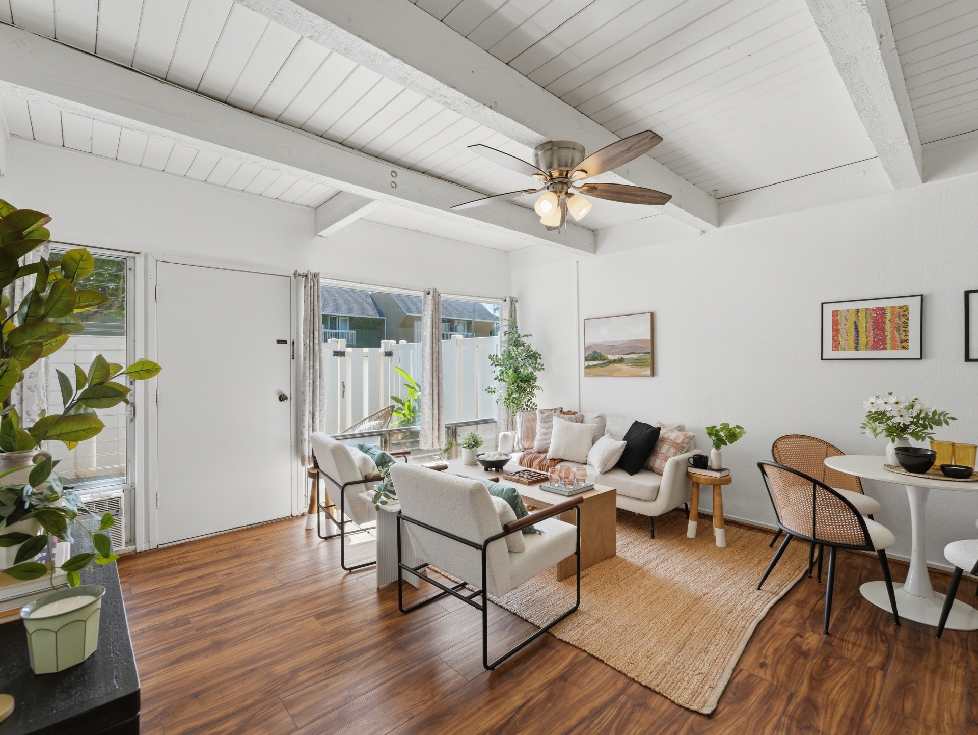 Bright living room with entry door and fenced courtyard view