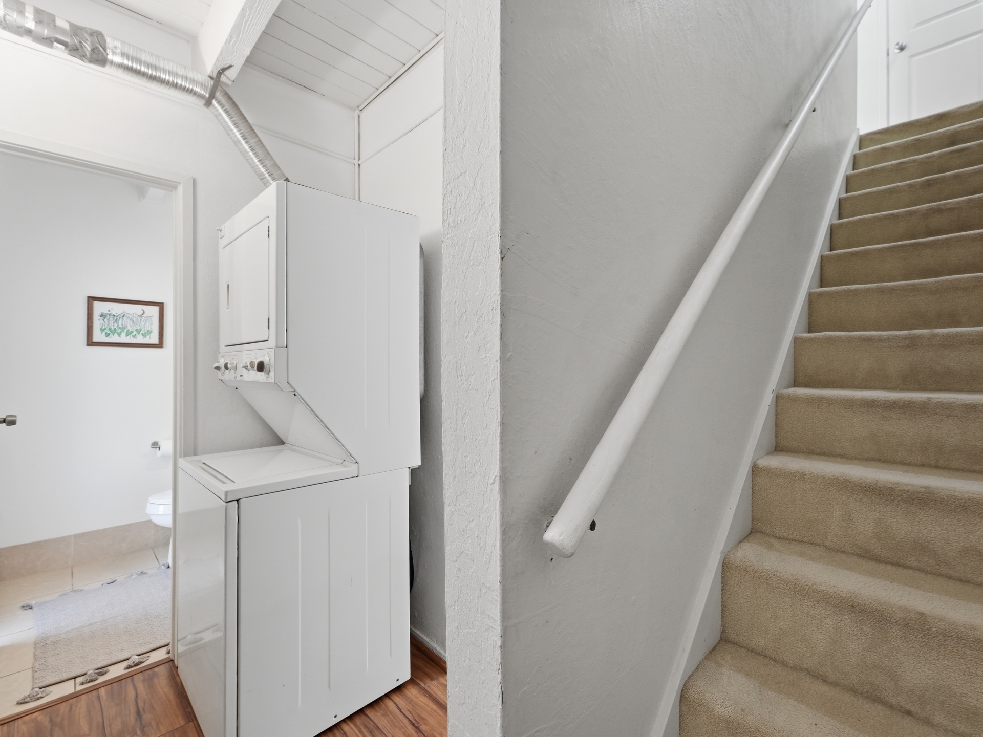 Carpeted staircase to upper level with laundry nook and half bath