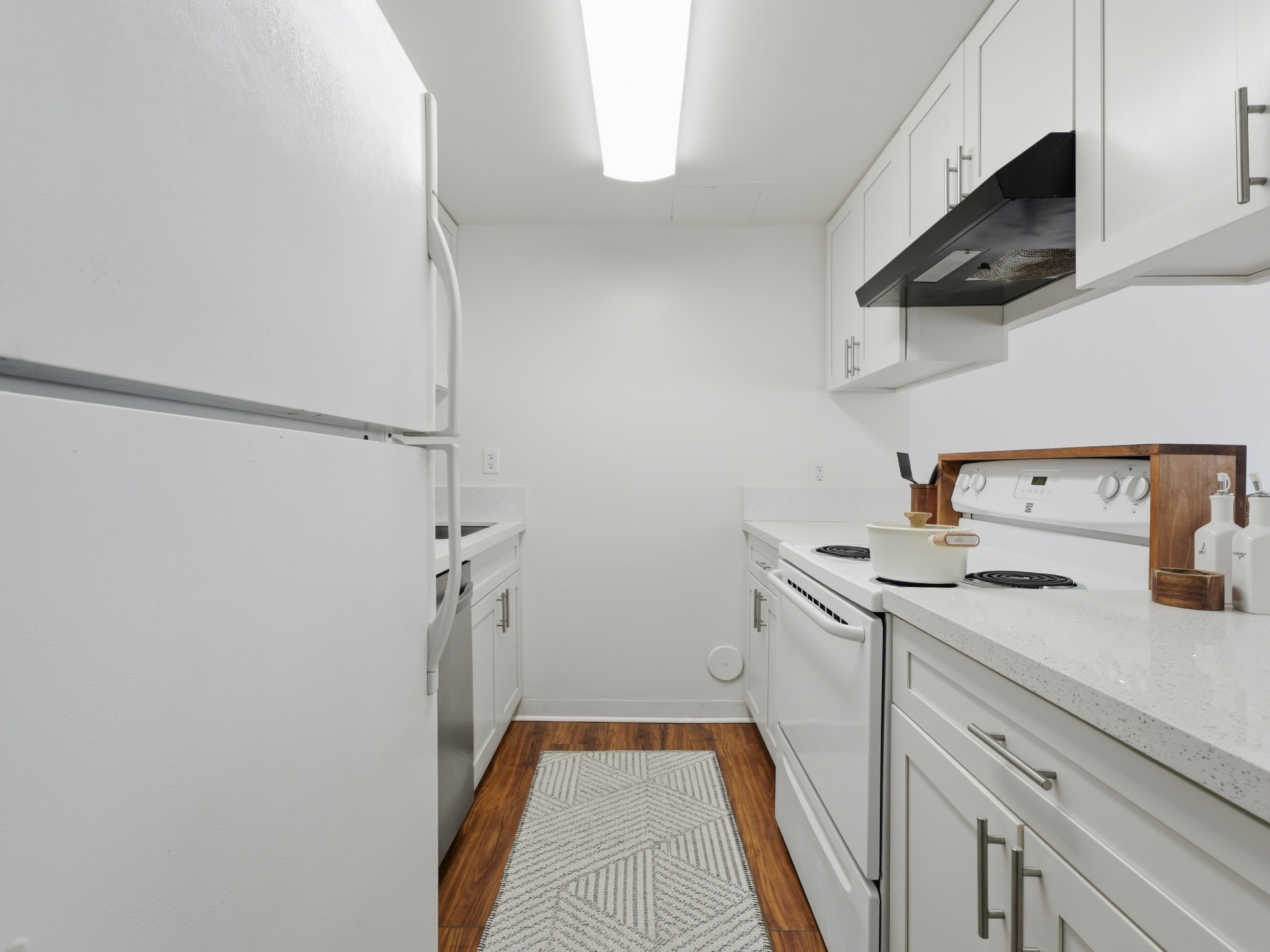 Galley kitchen view with full appliance suite and wood-look flooring