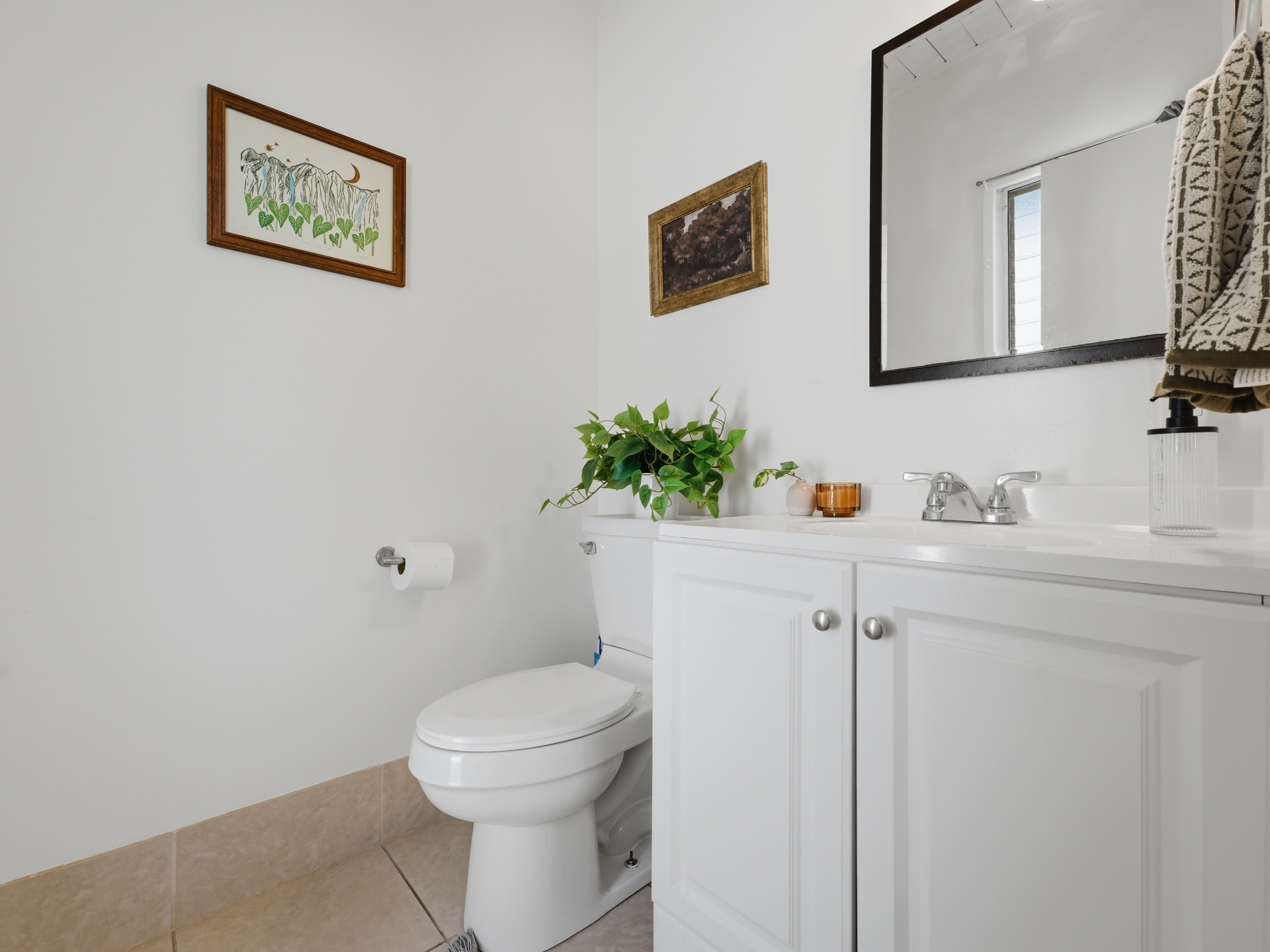 Half bath with white vanity, framed art and bright natural light