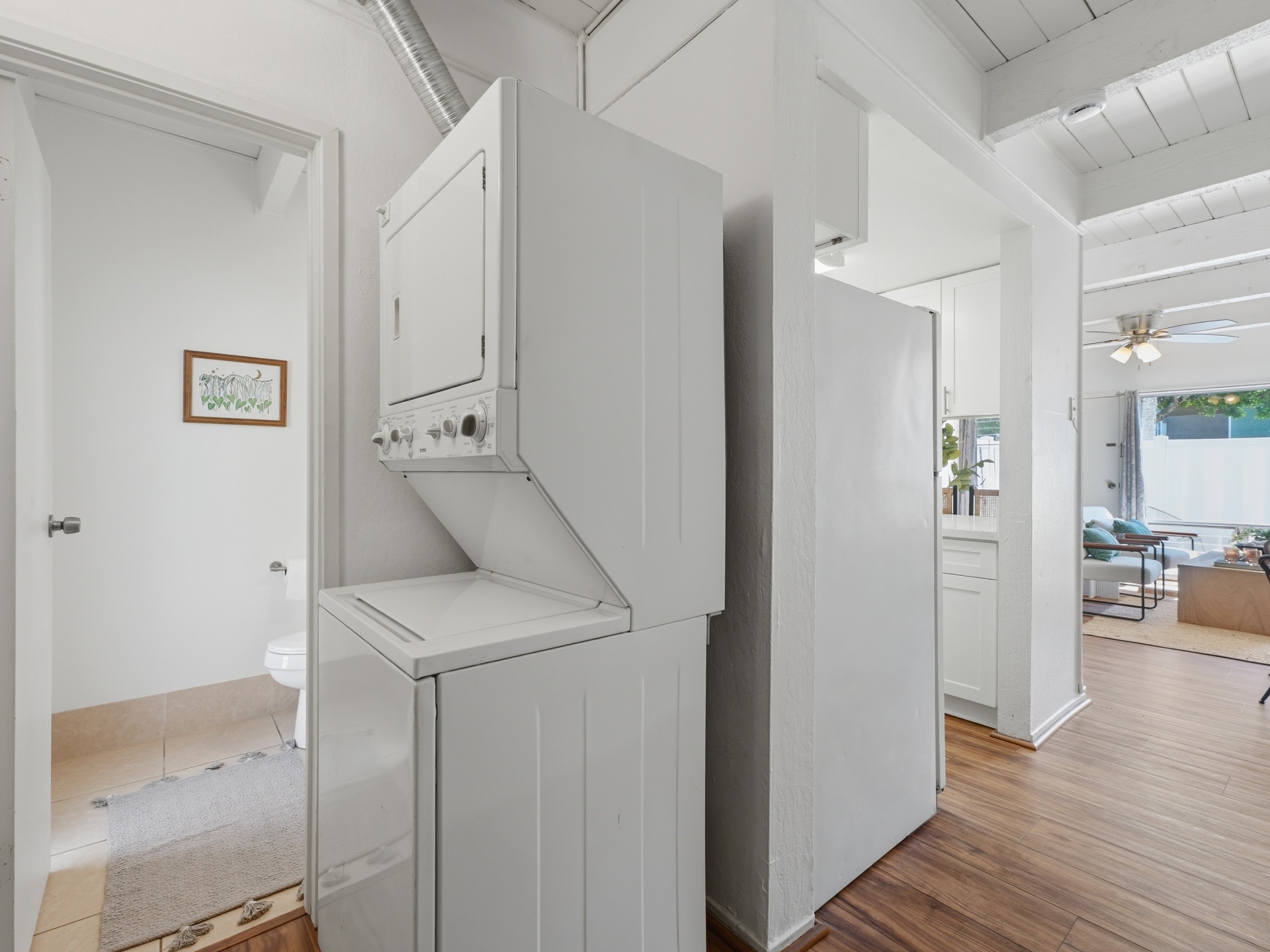 Downstairs laundry area with stacked washer/dryer and half bath beyond