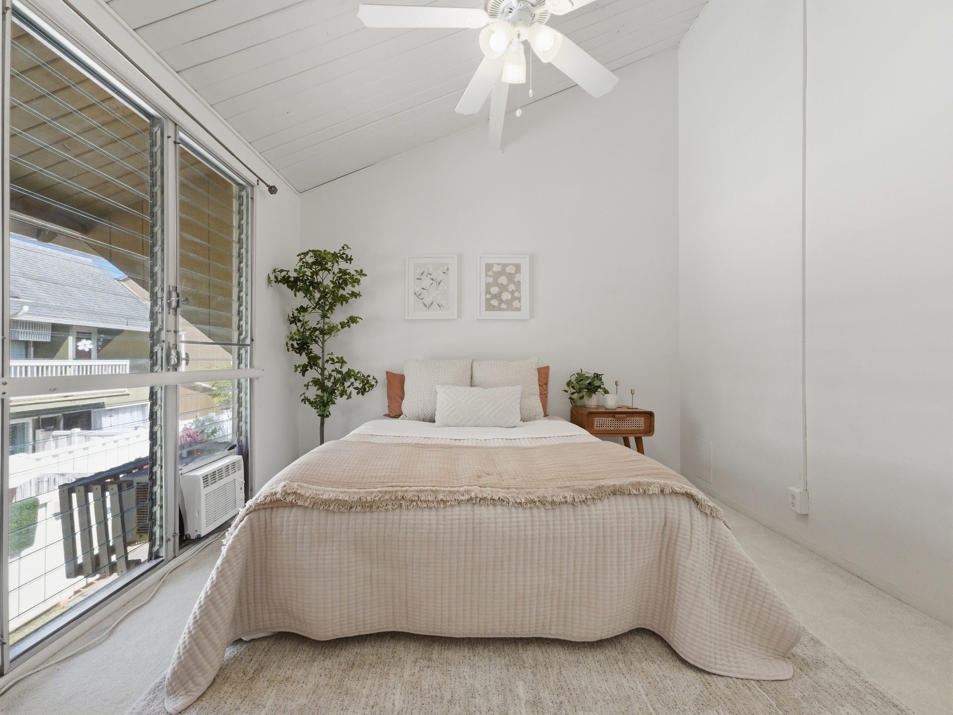 Bedroom with vaulted ceiling and large windows overlooking courtyard