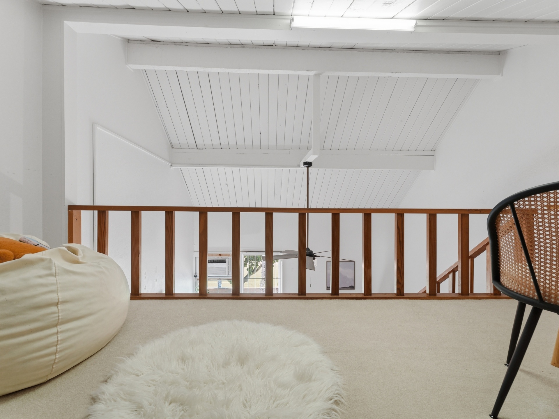 Open loft with sheepskin rug, bean bag and wood railing